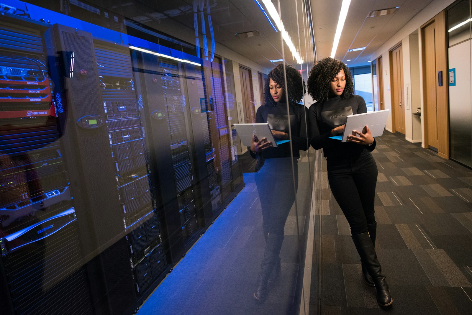 Two colleagues walking through a darkened corridor lined with illuminated data centre displays