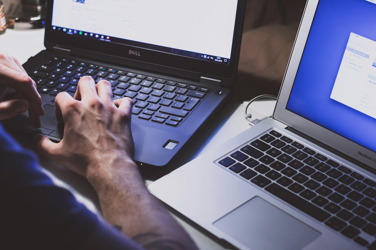 Hands typing on laptops at a shared desk