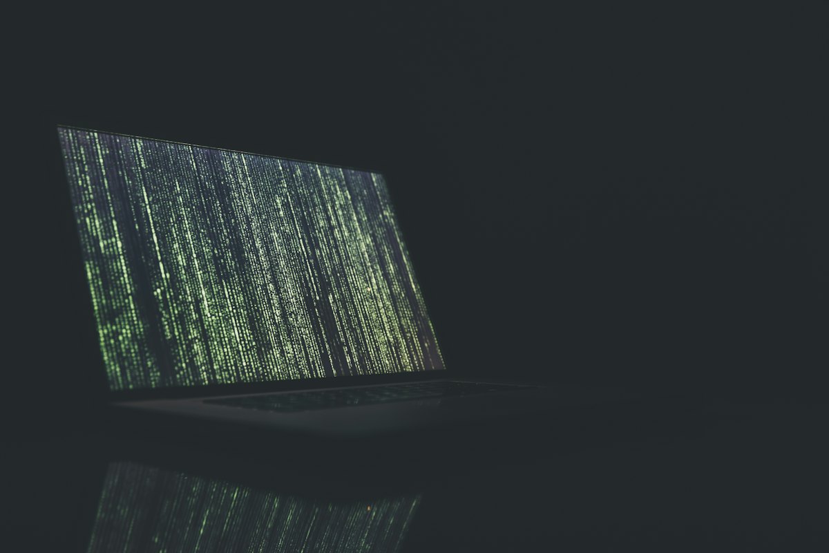 A laptop in a darkened room displaying cascading code