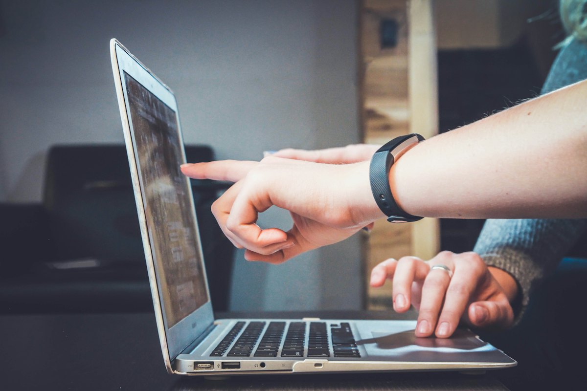 Two colleagues reviewing something on a laptop screen