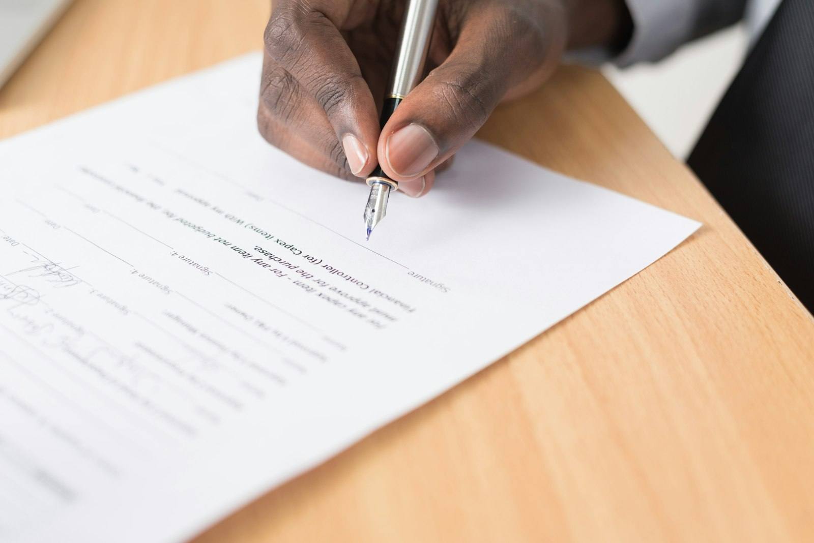 A hand signing a printed policy document
